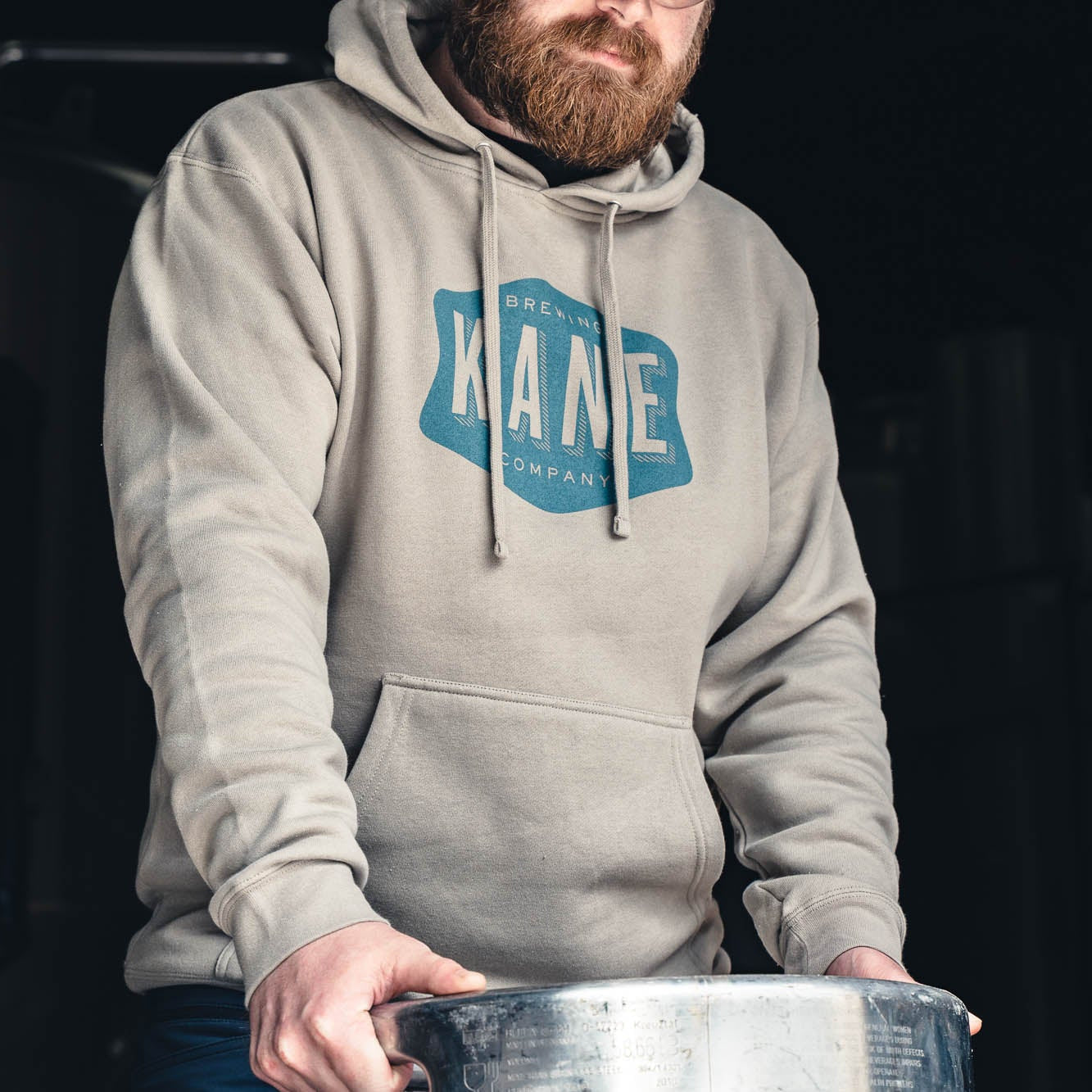 Person wearing a Kane hoodie with a logo, holding a keg.